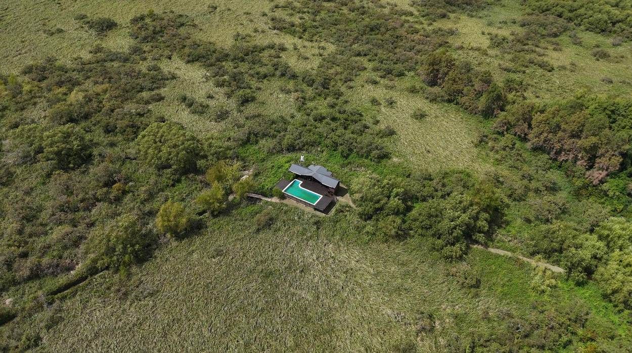 Vista aérea de la casa de invitados y la pileta en medio de la reserva natural